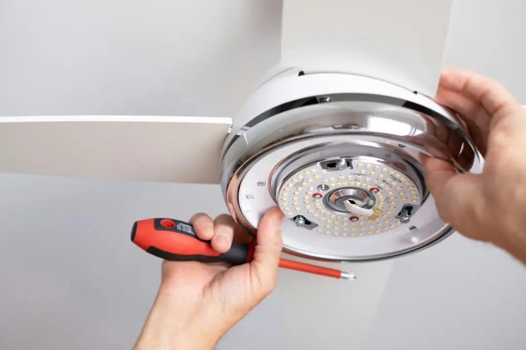 Close up on electrician man 's hands installing a paddle fan on the ceiling at home